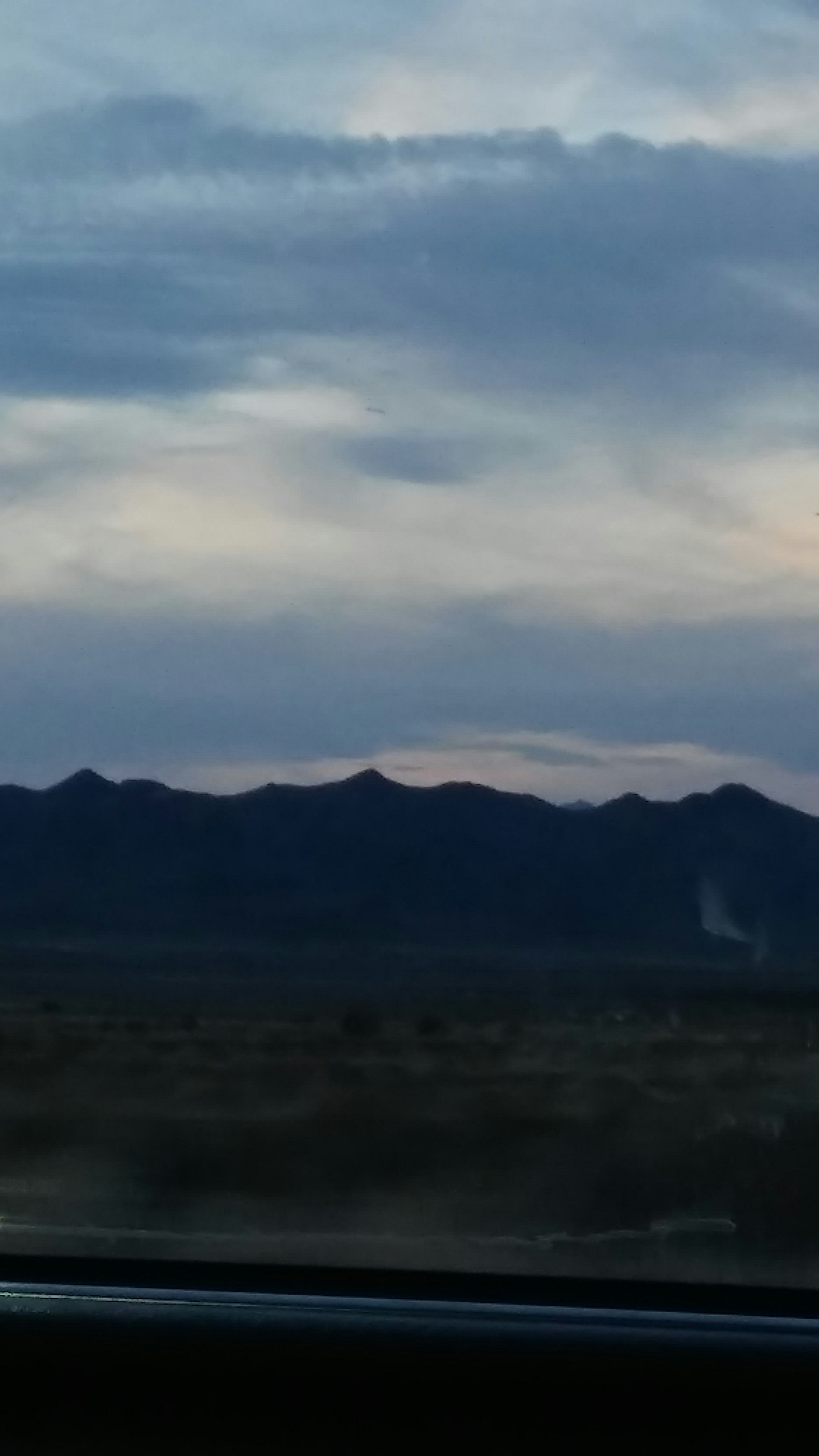 New Zealand mountain trail at dusk, dramatic dark sky, moody landscape, deep contrast between light and shadow