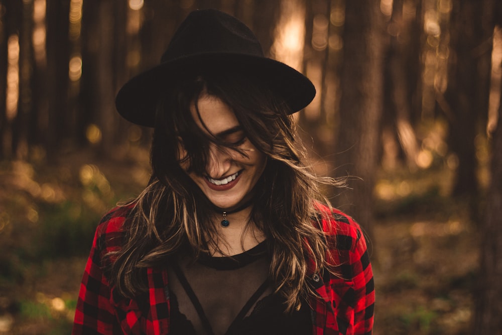 woman in fedora hat surrounded by trees