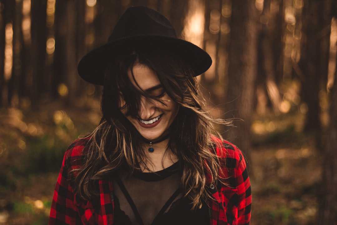 woman in fedora hat surrounded by trees