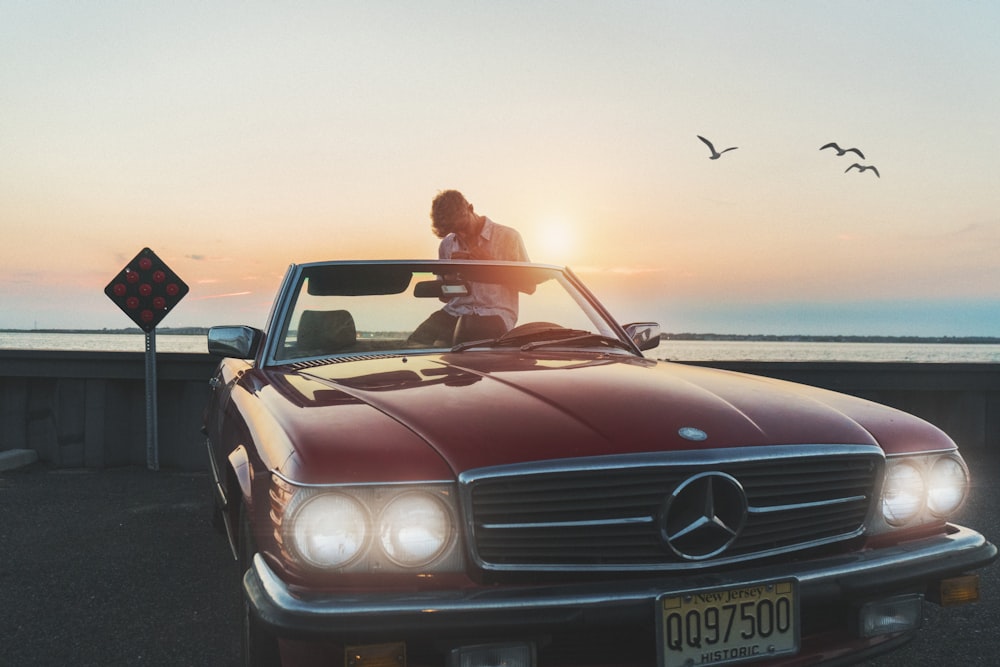 a man standing on top of a red car