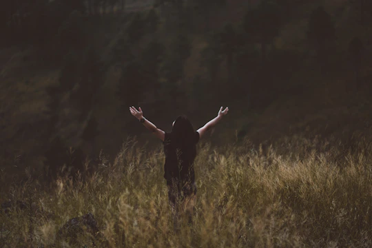 man raising arms between greenfield