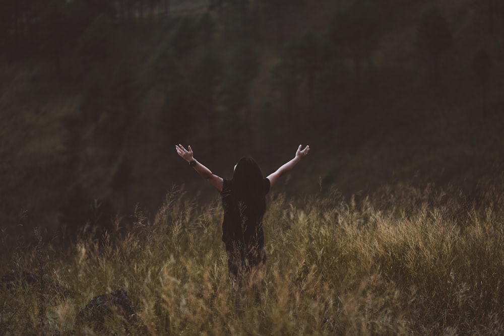 man raising arms between greenfield