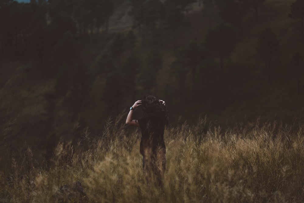 woman standing on green grass on mountain