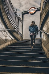 woman in blue denim button-up jacket walking on concrete stairs during daytime