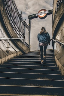 woman in blue denim button-up jacket walking on concrete stairs during daytime