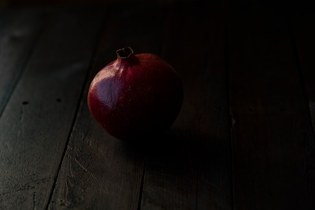 red pomegranate fruit on brown wooden surface