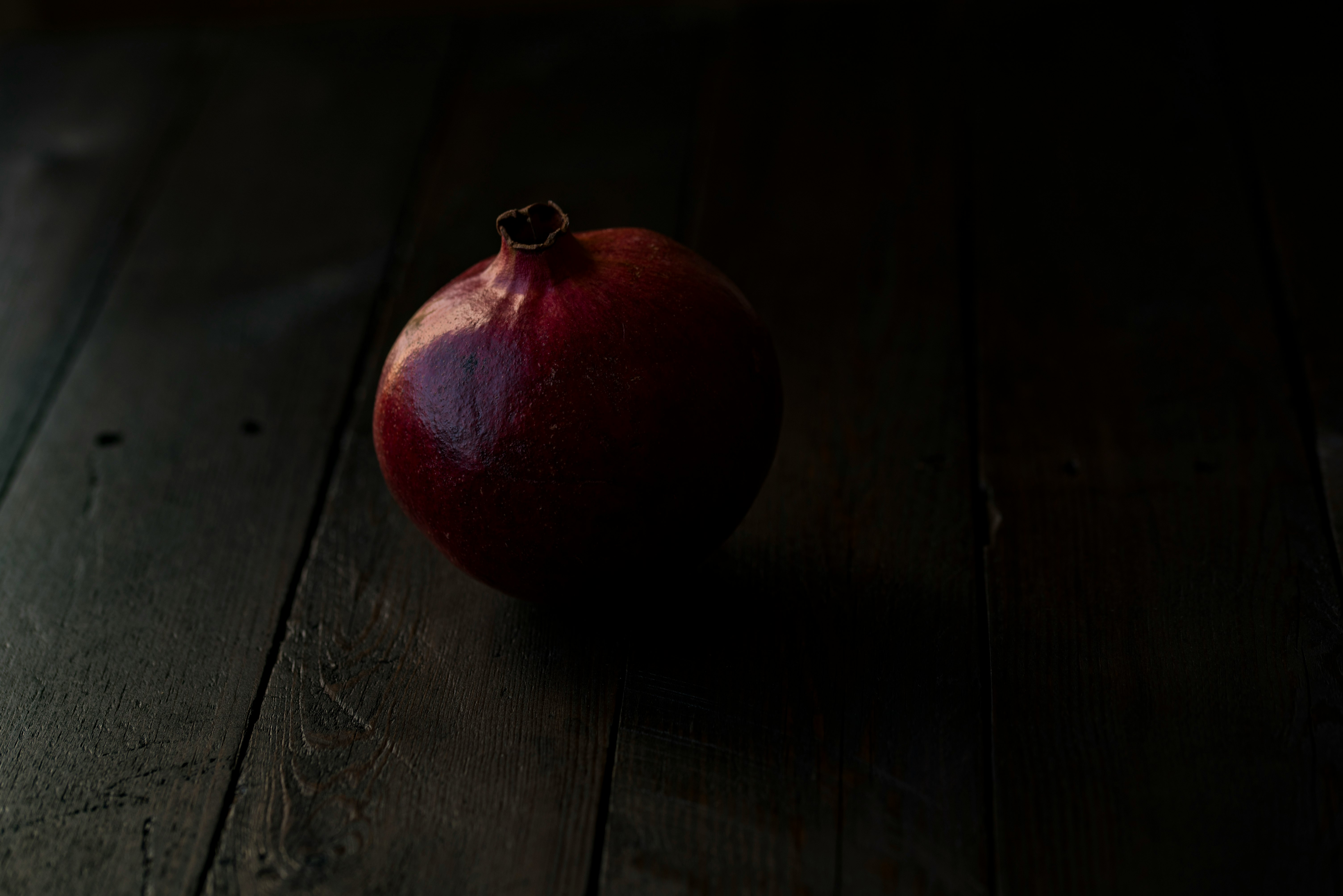 red pomegranate fruit on brown wooden surface