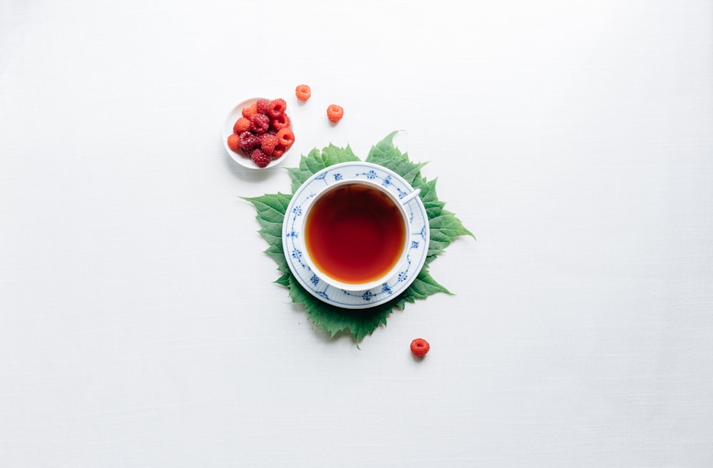 tasse ronde blanche avec soucoupe remplie de liquide rouge