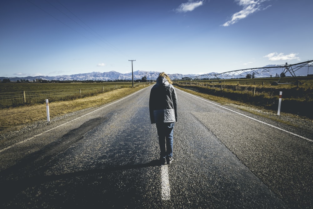 person walking on road under blue sky