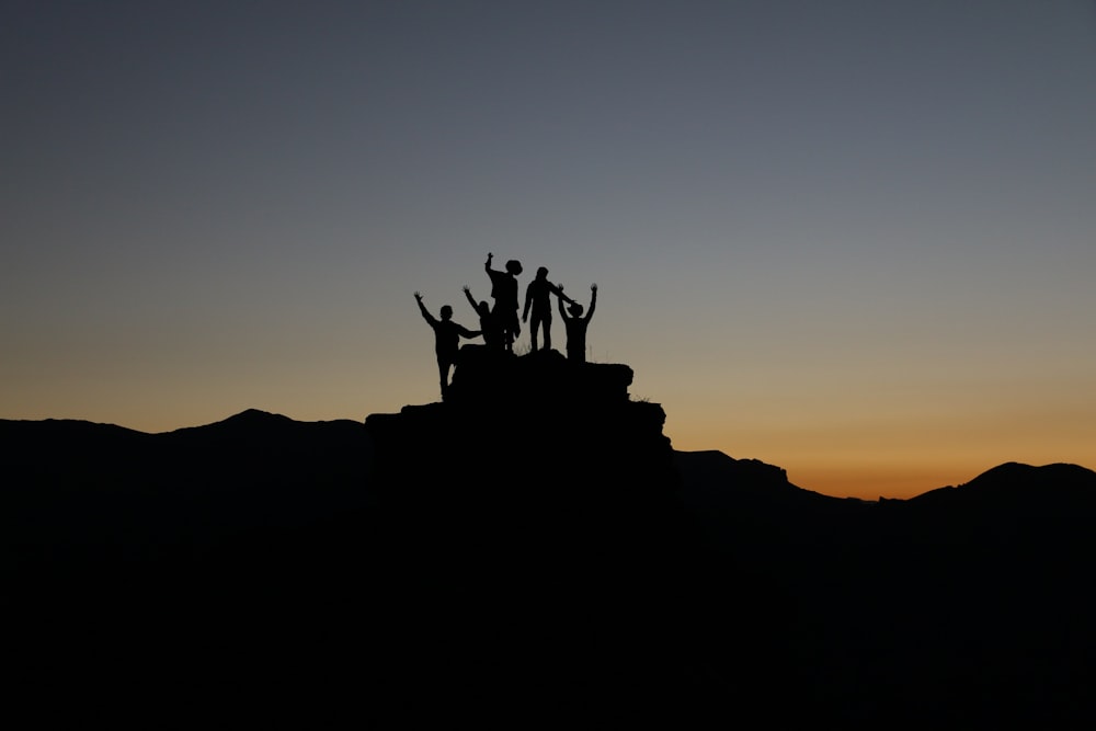 silhouette de personnes debout sur les hautes terres pendant les heures dorées