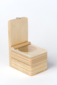 A wooden box with smooth edges and a latch on top. The box is open, revealing a round compartment inside. The wood has a light, natural finish with visible grain patterns.