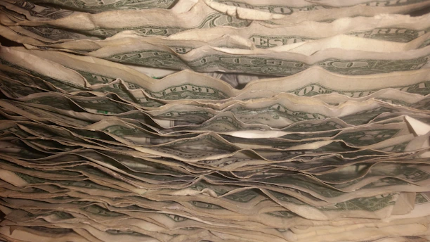 Close-up of hands holding a small stack of worn bills, symbolizing financial struggle and hope.