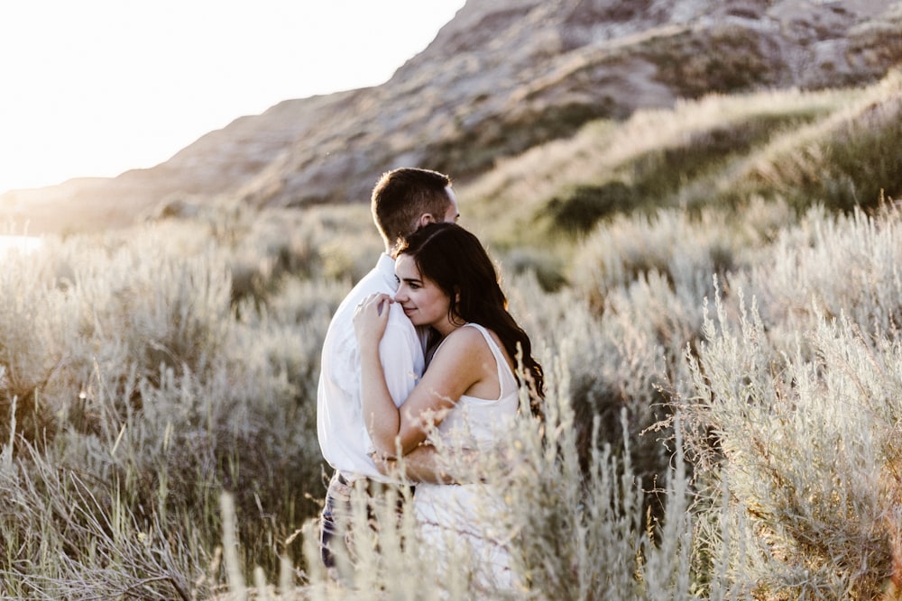 hombre abrazando a una mujer cerca de la montaña