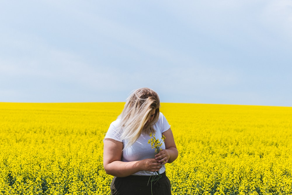 woman standing and holding flowers on flower field