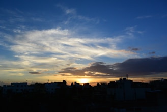 A digital rendering of a cloudy sky over a cityscape at sunset