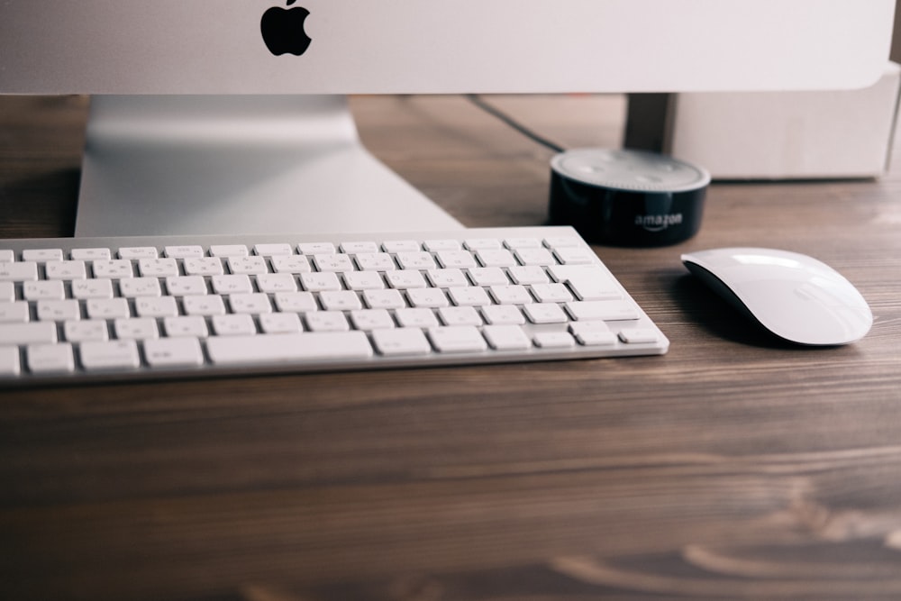 selective focus photography if silver iMac, Apple wireless keyboard, Magic Mouse, and black Amazon Echo Dot 2nd generation at table