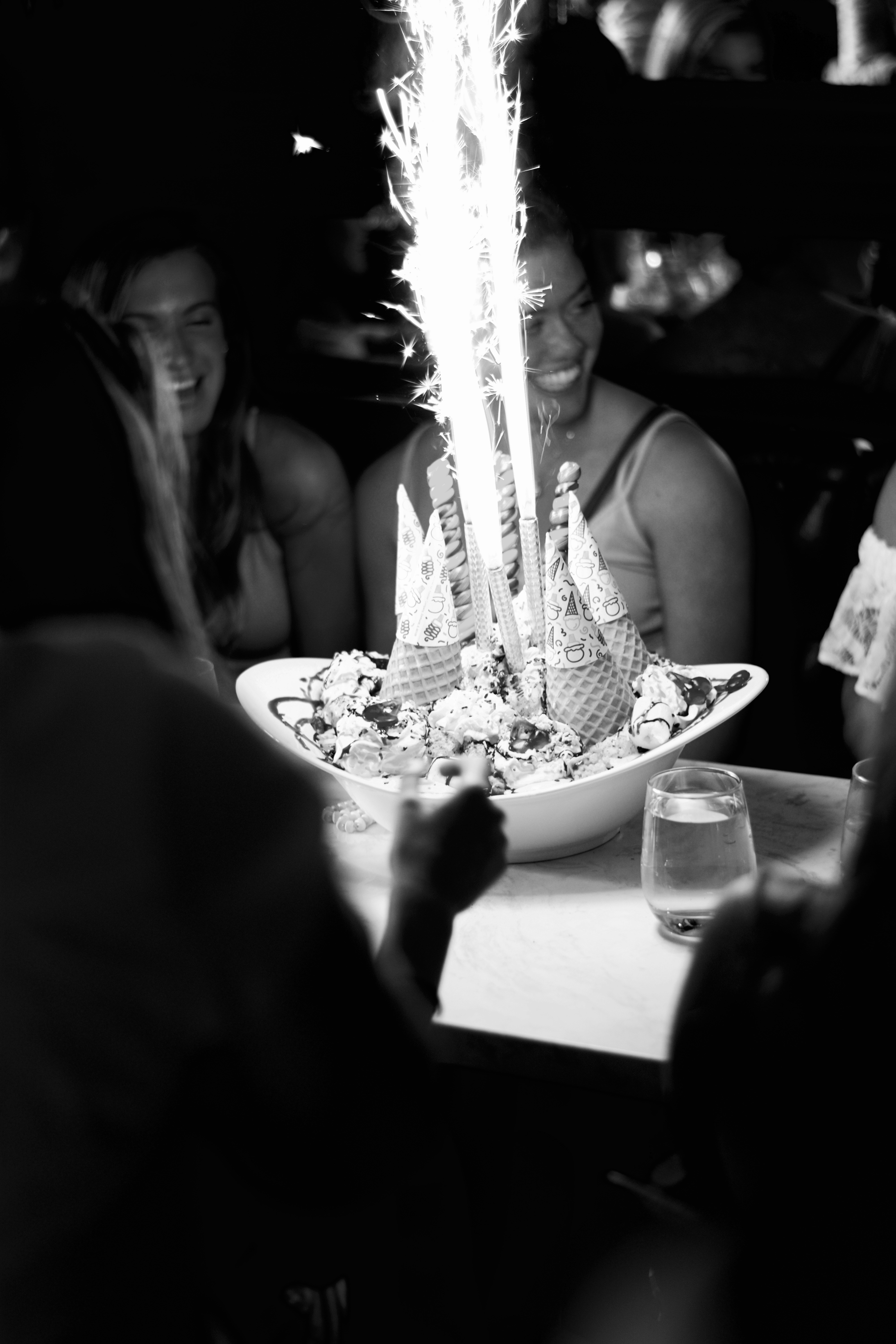 Birthday celebration food spread with colorful desserts, dark party venue, low ambient party lighting