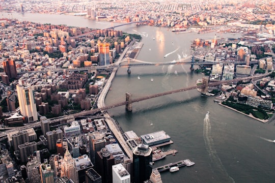 body of water between island with building and bridge at daytime in Brooklyn Bridge United States