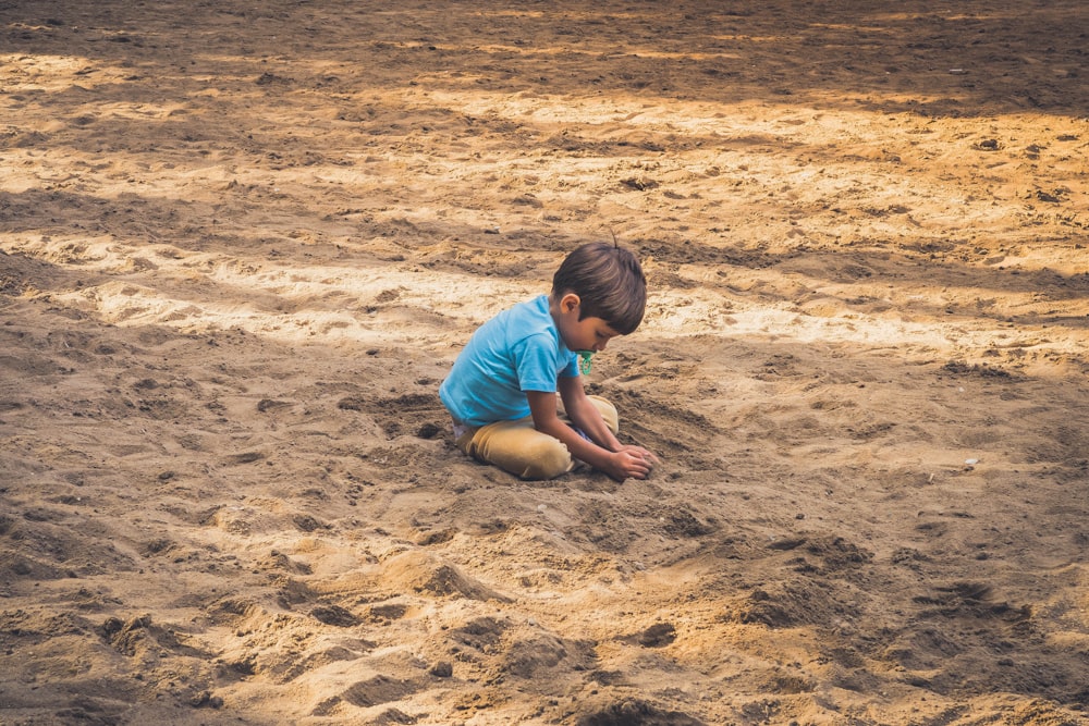 boy playing on sand during daytime