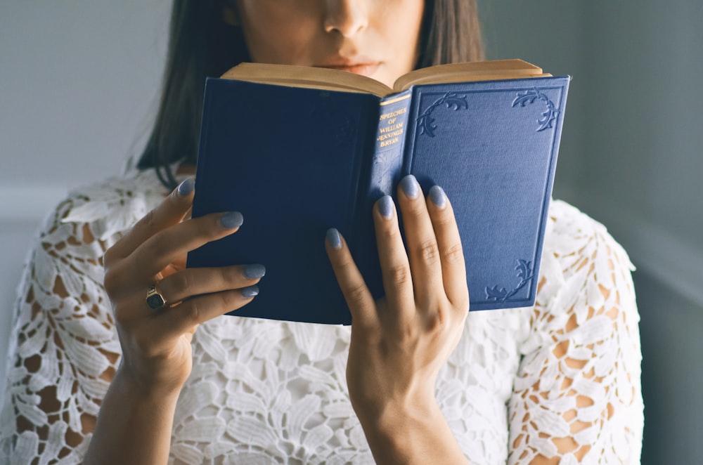 woman wearing white floral top reading bible