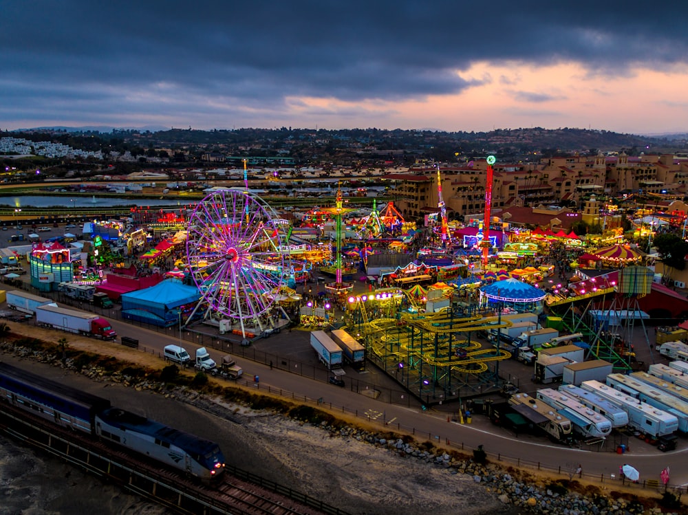 fotografia de alto ângulo do parque de diversões multicolorido ao lado do trem durante o dia