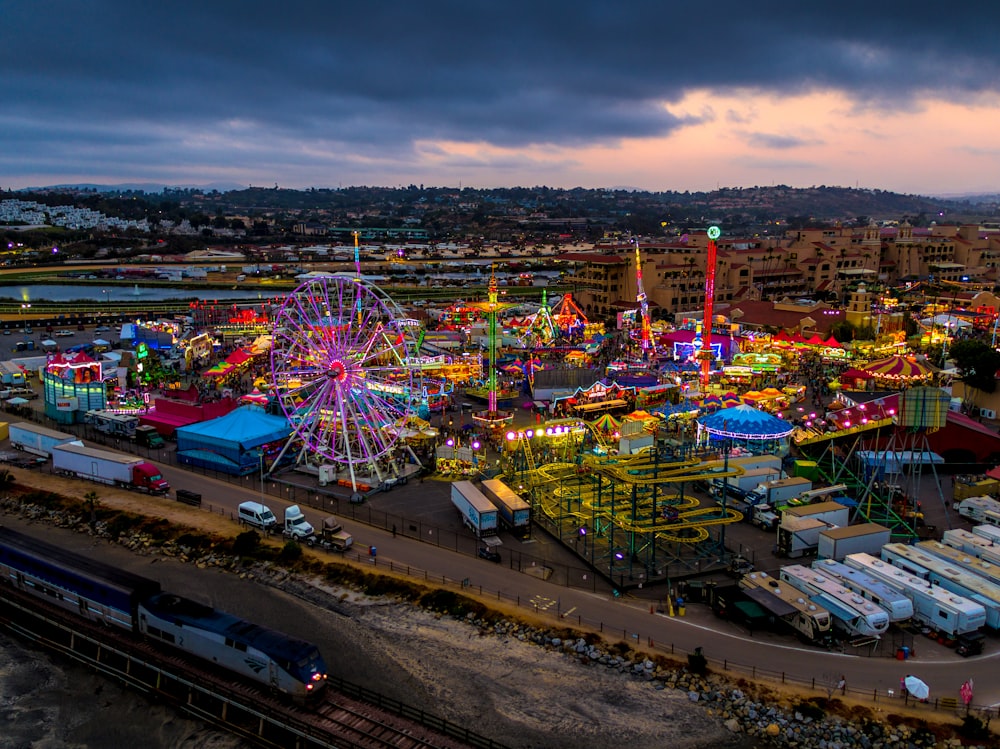 high-angle photography of multicolored amusement park beside train during daytime