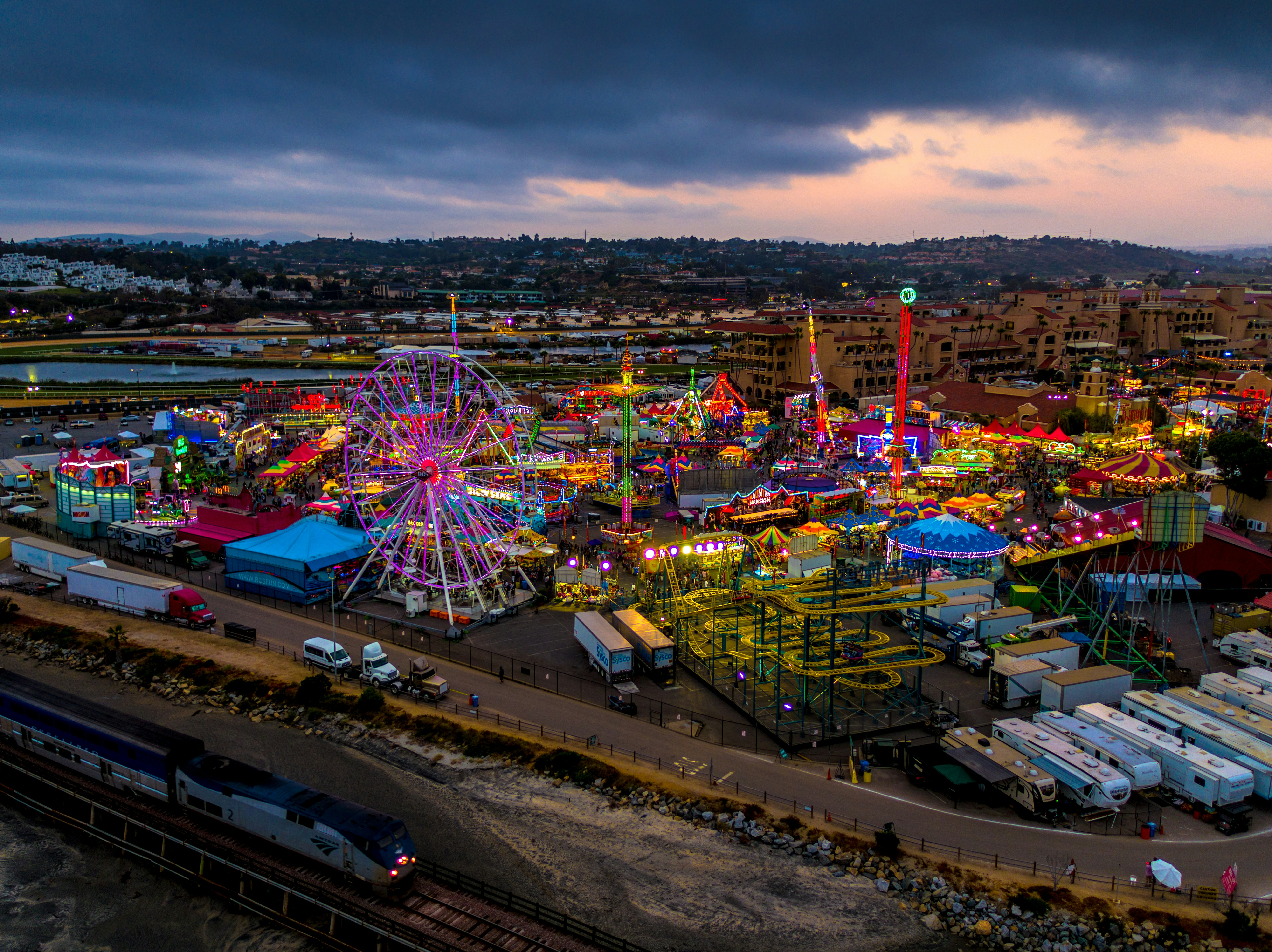 high-angle photography of multicolored amusement park beside train during daytime