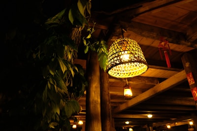 Rustic rattan lamps casting warm light over a cozy dining table set with olive green accents.
