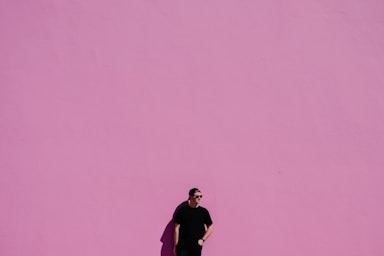 negative space for photo composition,how to photograph man against pink wall; man in black shirt on pink background