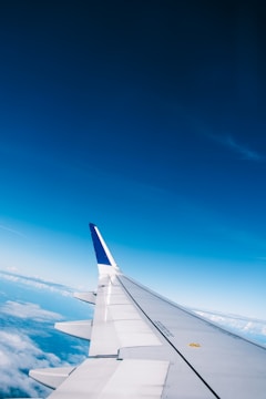 A team of aviation experts conducting a safety inspection on an aircraft wing under clear blue skies.