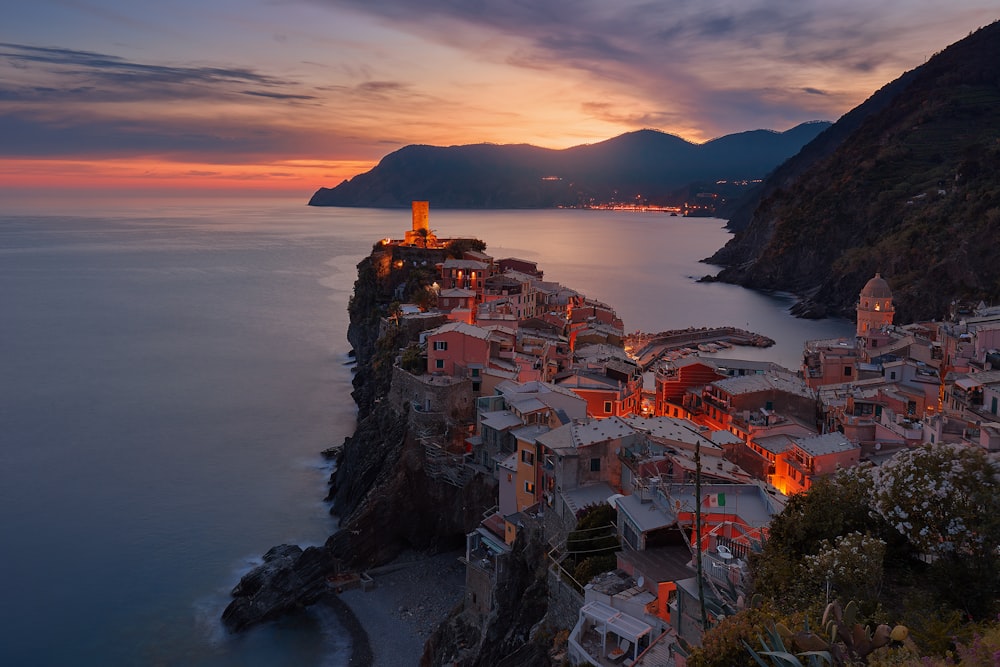 Coastal town of Vernazza in Italy, its buildings glowing orange as the sun sets behind a mountain