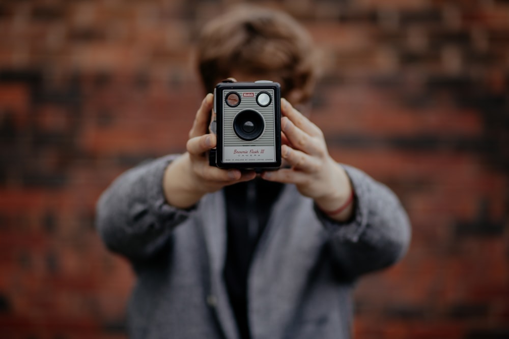 selective focus photography of person holding grey and black camera