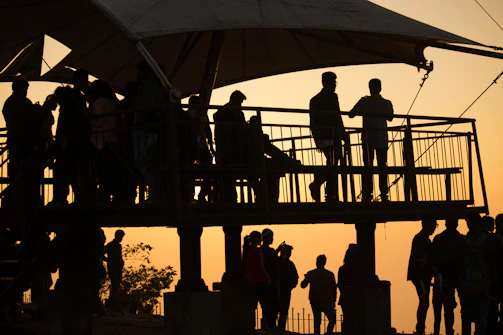 A cinematic frame showing a sunset silhouette of a storyteller speaking to an engaged audience.