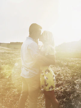 A candid image of a couple embracing in a sunlit field with charcoal and terracotta hues.