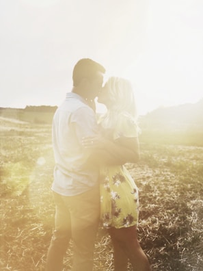 A couple embracing in a sunlit field during their prenup photo session.