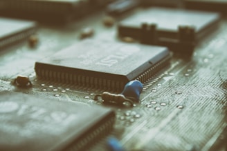 A close-up view of a computer motherboard with several microchips and electronic components. The focus is on the intricate details of the circuit pathways and the array of pins on the chips.