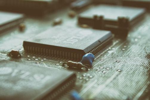 A close-up view of a computer motherboard with several microchips and electronic components. The focus is on the intricate details of the circuit pathways and the array of pins on the chips.