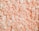 A collection of white and light pink packing peanuts densely packed together, creating a textured surface with curled and cylindrical shapes.