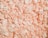 A collection of white and light pink packing peanuts densely packed together, creating a textured surface with curled and cylindrical shapes.