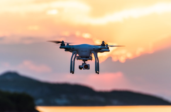 A sleek drone hovering over a scenic landscape during golden hour.