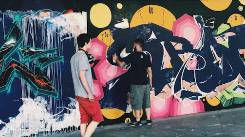 Volunteers painting a colorful mural on a neighborhood building wall.