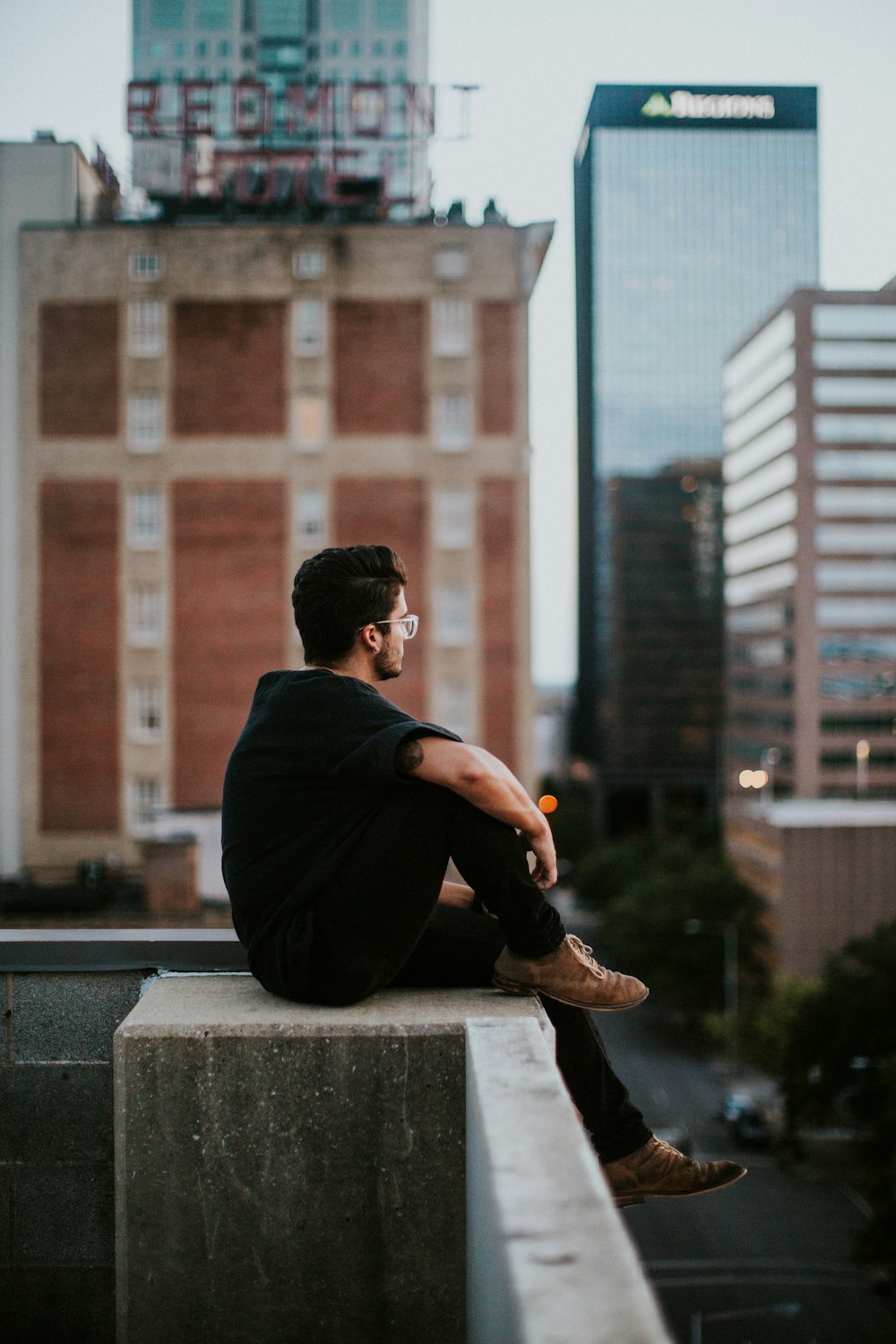 homem sentado no edifício de concreto branco durante o dia