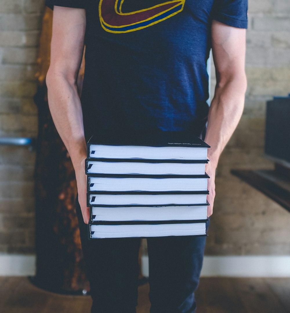 man holding stack of books