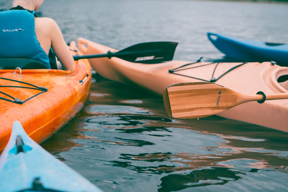 Persona che cavalca su un kayak arancione durante il giorno