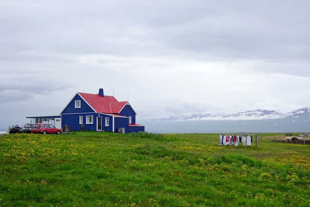maison rouge et blanche sur le champ d’herbe verte sous les nuages blancs pendant la journée