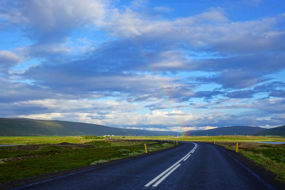 Carretera de asfalto gris bajo nubes blancas y cielo azul durante el día