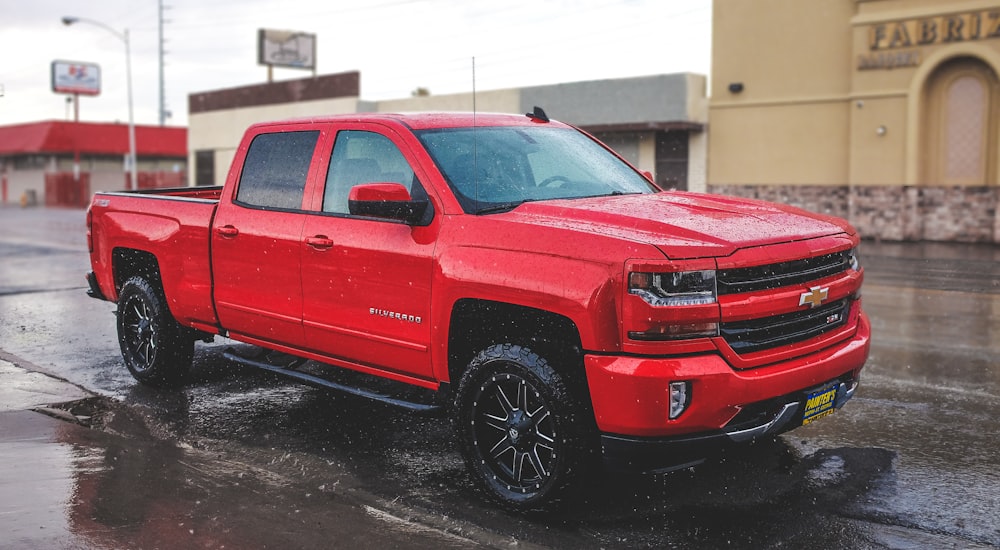 a red truck is parked on a wet street