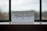 A piece of paper with the word 'mindfulness' written in elegant, flowing cursive sits on a windowsill. The background shows an out-of-focus view through a window, with a blend of muted colors.