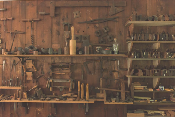 A rustic workshop with various agricultural tools neatly arranged on wooden shelves.