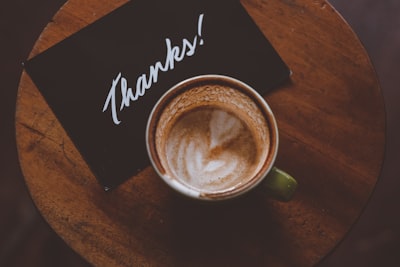 flat lay photography of coffee latte in teacup on table gratitude teams background